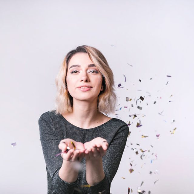 Smiling woman blowing confetti